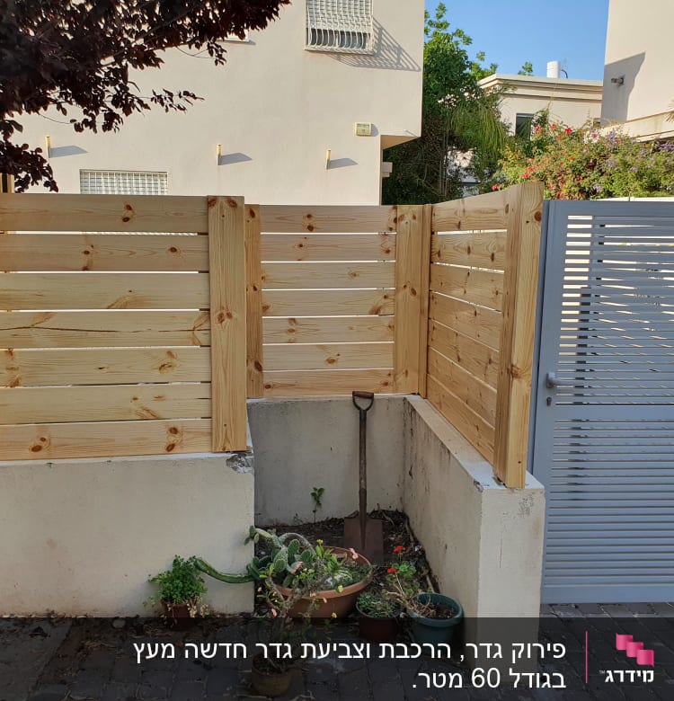 גדר עץ חדשה ליד שער מתכת בגינה